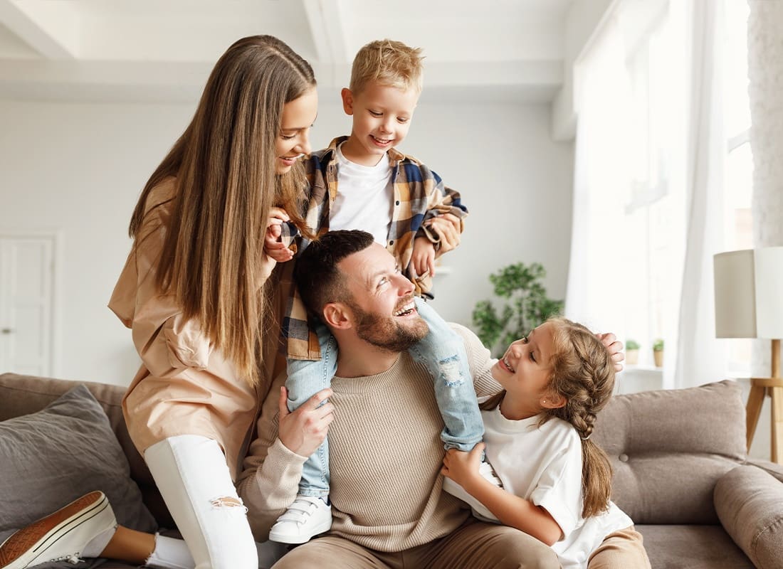 Insurance Solutions - Happy Family With Mother and Father and Kids Having Fun at Home on Couch